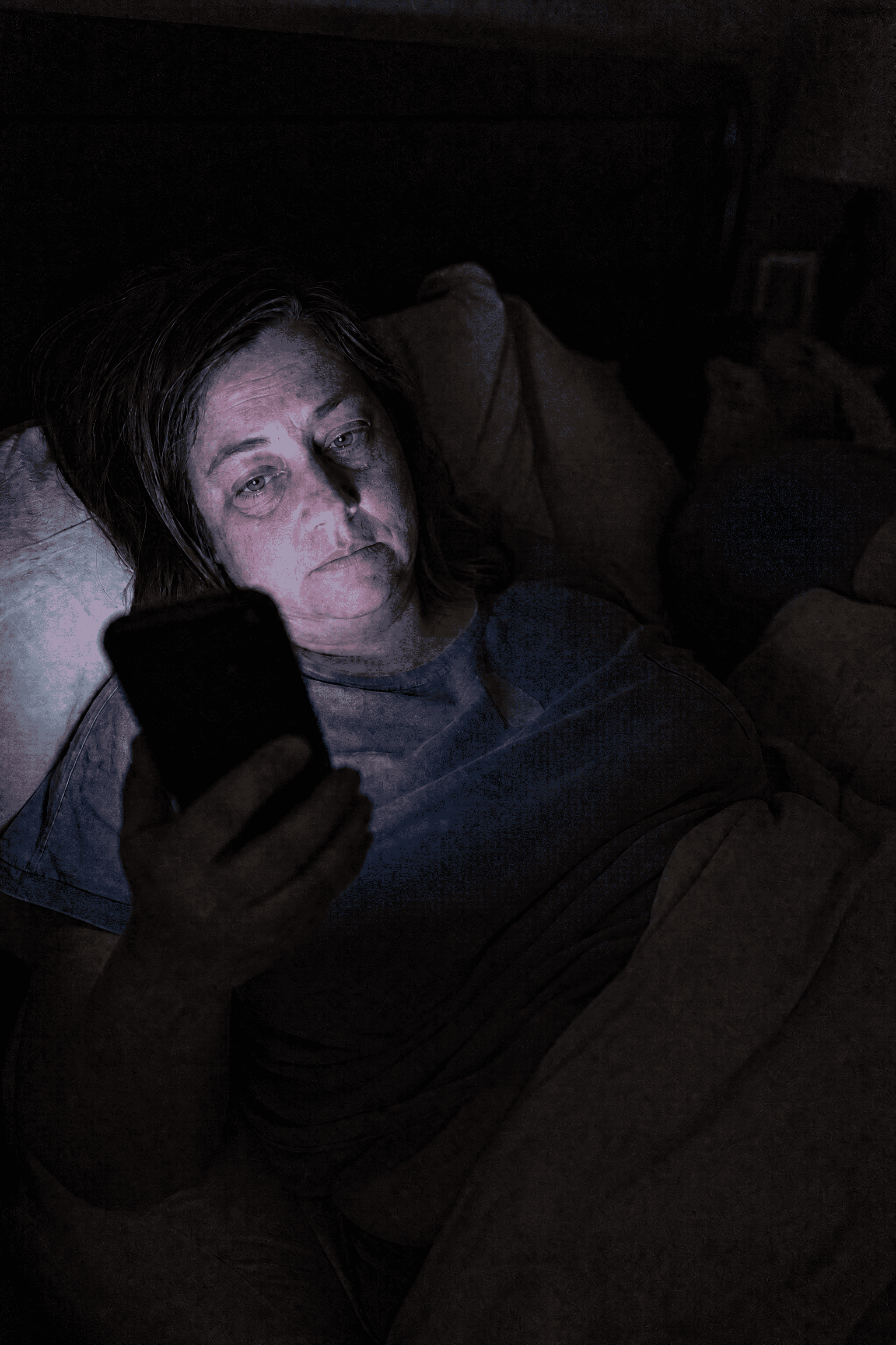 Tania awake at 1 a.m. in a dark bedroom, face lit by her phone, exhausted but hopeful